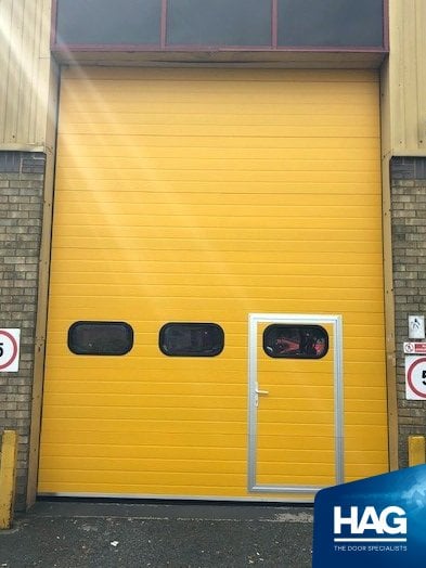 overhead sectional industrial door fitted with personnel door. Yellow powder coated.